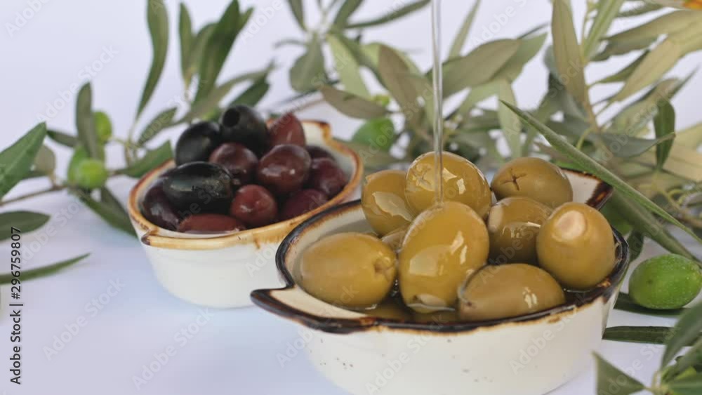 Olive oil flows through the olive. Closeup of green and black olives. A lot of berries in a cup and green leaves on a branch. Olive oil flows through the olive. Closeup of green and black olives. A lot of berries in a cup and green leaves on a branch.