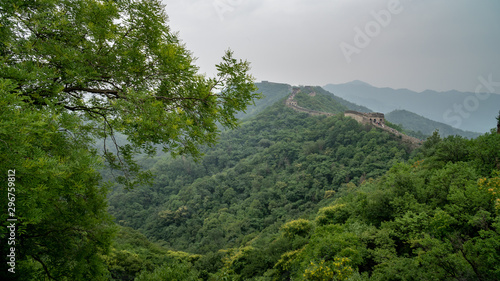 Great Wall of China with a green trees  and moutains in a background.