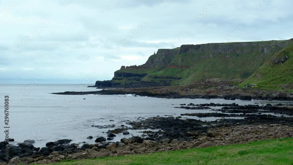Wide handheld shot of the coastal view of the Northern Ireland Giants Causeway coastline, green mossed basalt lava rock formations, and beach. Background shot, cloudy daytime no people and copy space. Wide handheld shot of the coastal view of the Northern Ireland Giants Causeway coastline, green mossed basalt lava rock formations, and beach. Background shot, cloudy daytime no people and copy space.