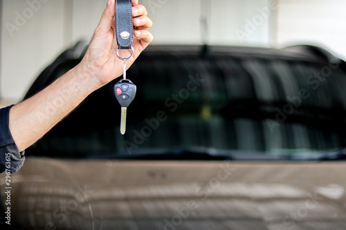 A man holding car key on black car background, journey of life concept