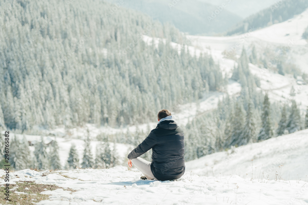 Young man sitting and enjoying the mountain view in Carpathians. Back view.
