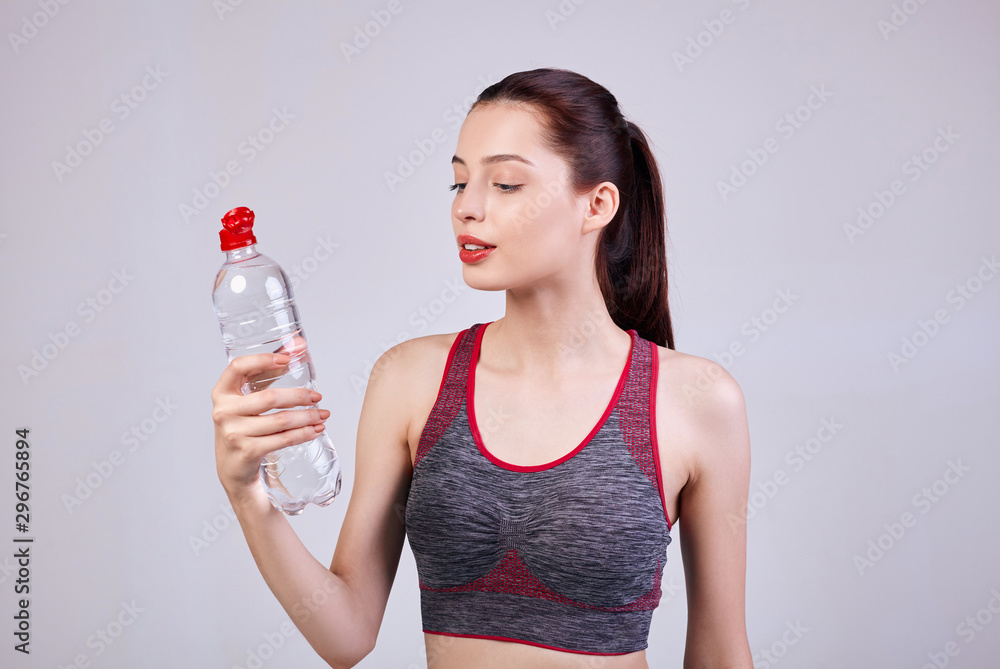 young beautiful girl with dark brown hair with full lips with a bottle water in her hand. young beautiful girl with dark brown hair with full lips with a bottle water in her hand.
