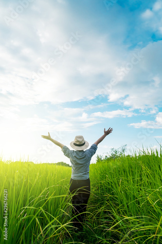 Behind the farmer woman's hands raised in the sky in a field with sky background