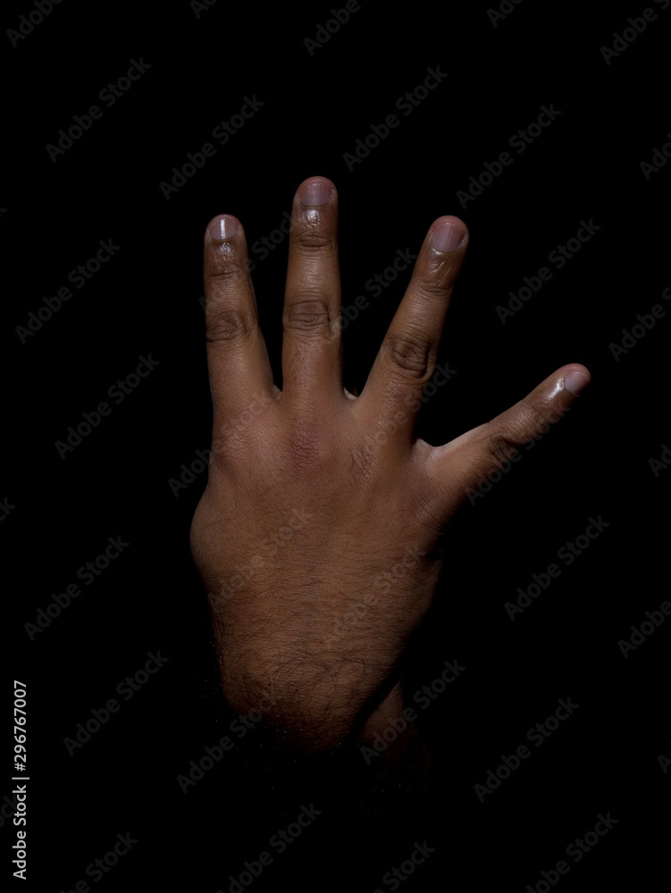 Low key photo of a brown man showing the back of his hand with four fingers sticking out to show the number four Low key photo of a brown man showing the back of his hand with four fingers sticking out to show the number four