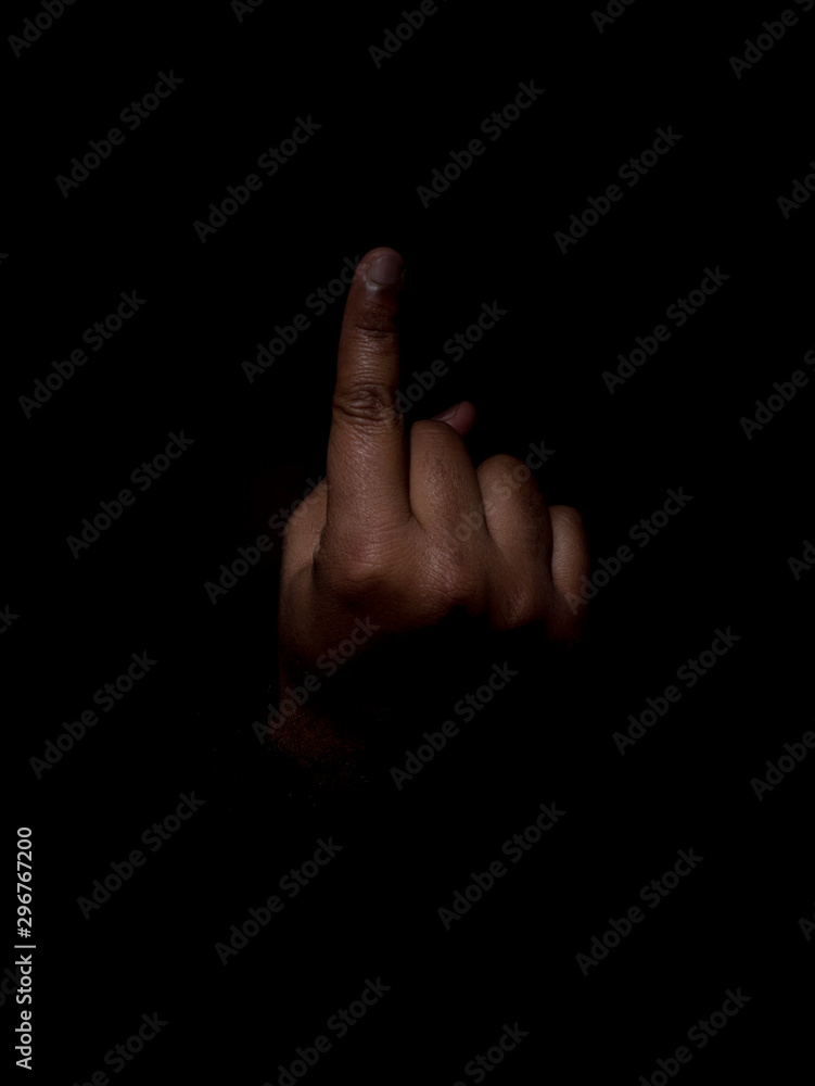 Low key photo of a brown man showing the back of his hand with the index finger out on a plain black background Low key photo of a brown man showing the back of his hand with the index finger out on a plain black background