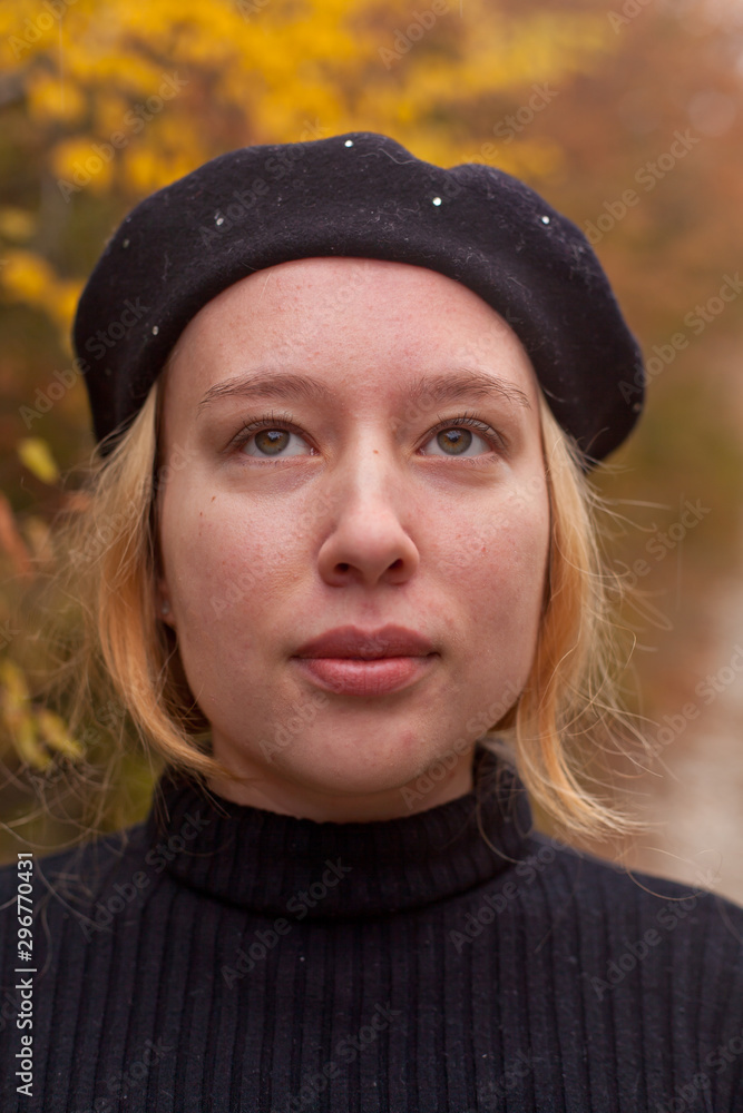 Fototapeta premium Blondy girl in black sweater and beret stands in the autumn in the park