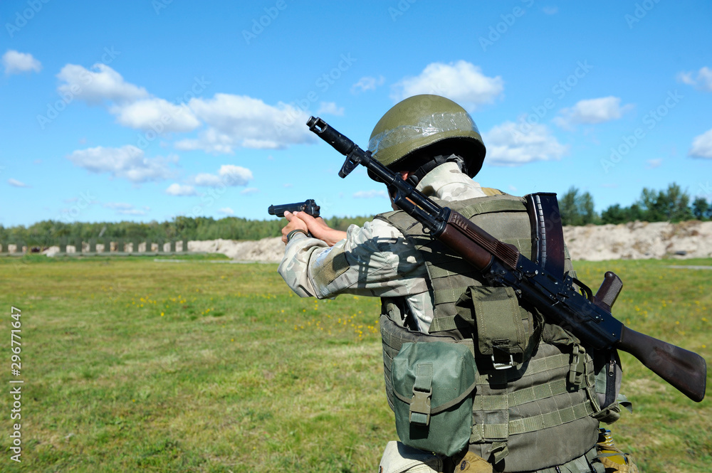 On the military shooting range, training: Fully equipped soldier aiming at cockshies with a gun On the military shooting range, training: Fully equipped soldier aiming at cockshies with a gun