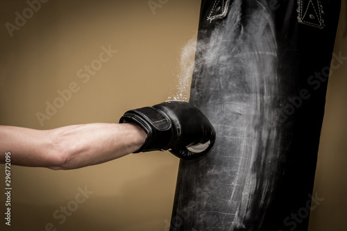 Hand of boxer and punching bag over yellow background
