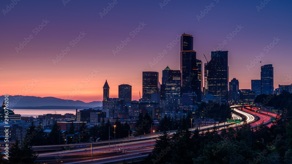 Seattle skyline, at sunset. The cars along the highway are creating light trails, due to a slow shutter speed