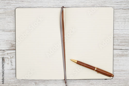 Blank brown journal with pen on a weathered whitewash wood background photo