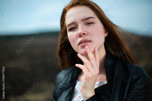 The red-haired beauty thoughtfully holds her chin with her hand