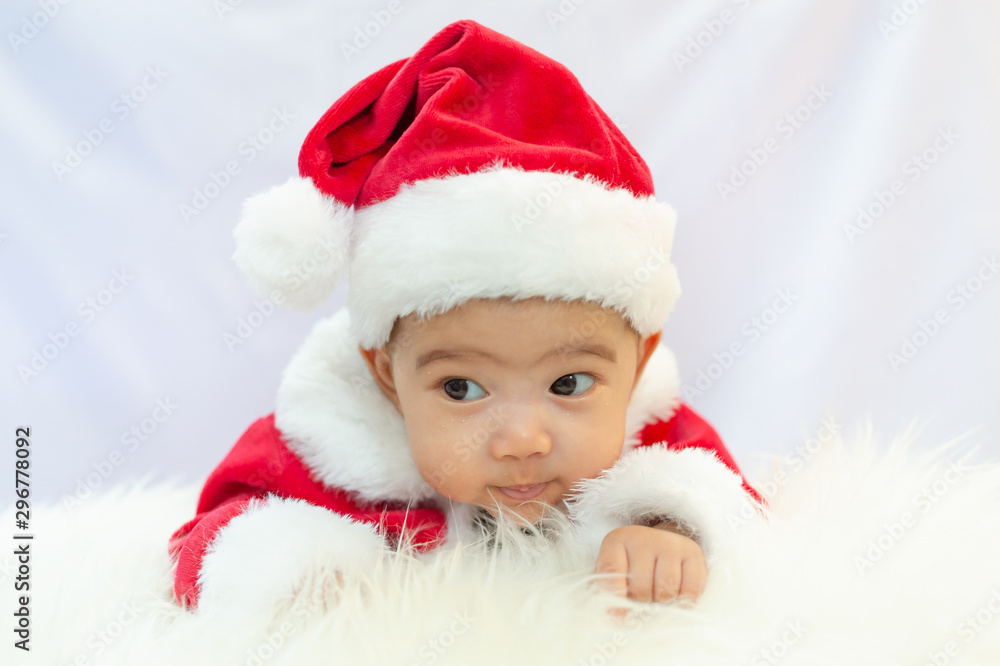 baby girl wearing red Santa Claus costume sit on white fur carpet. Concept of celebrates Christmas and New Year's holidays. baby girl wearing red Santa Claus costume sit on white fur carpet. Concept of celebrates Christmas and New Year's holidays.