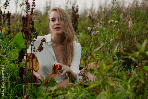 Fotografie A long-haired fairy sits in a thicket of plants