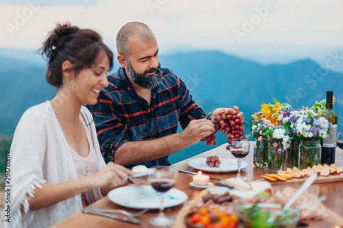 Friends and family gathered for picnic dinner for Thanksgiving. Festive young people celebrating life with red wine, grapes, cheese platter, and a selection of cold meats