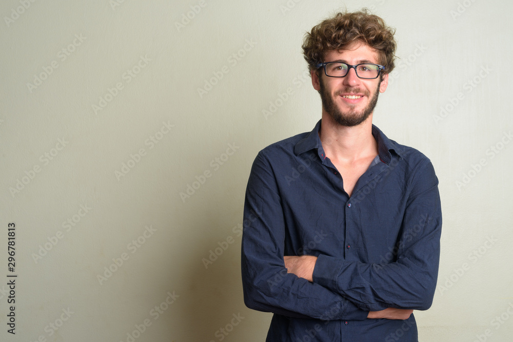 Obraz premium Happy young bearded businessman smiling with arms crossed