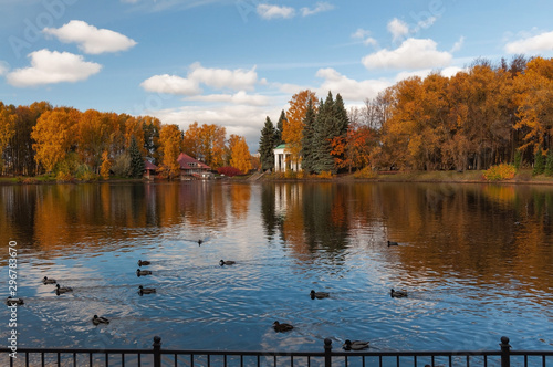 Colorful trees and a beautiful rotunda on the banks of a pond in a park on a sunny autumn evening