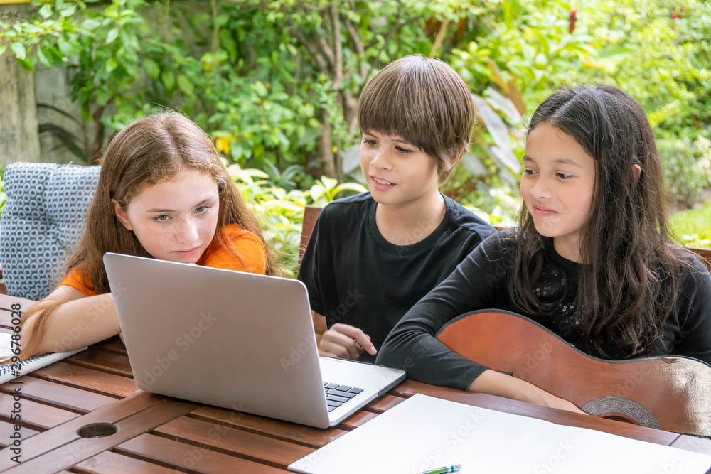 Children, boy and girl, using laptop computer for online learning in garden at home Children, boy and girl, using laptop computer for online learning in garden at home