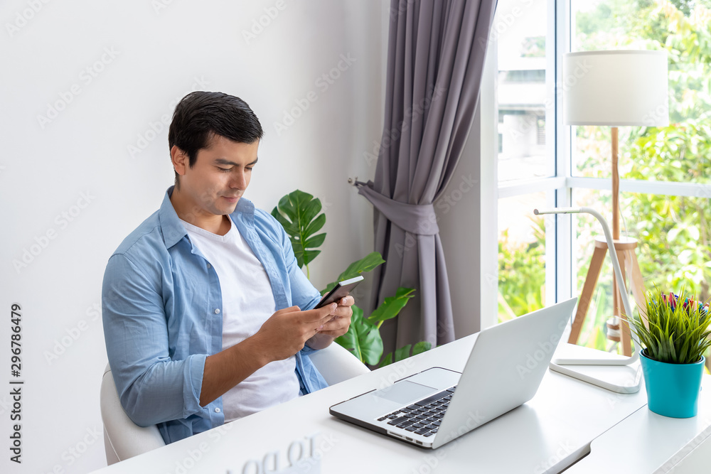 Attractive man is working at home with computer notebook and using mobile phone