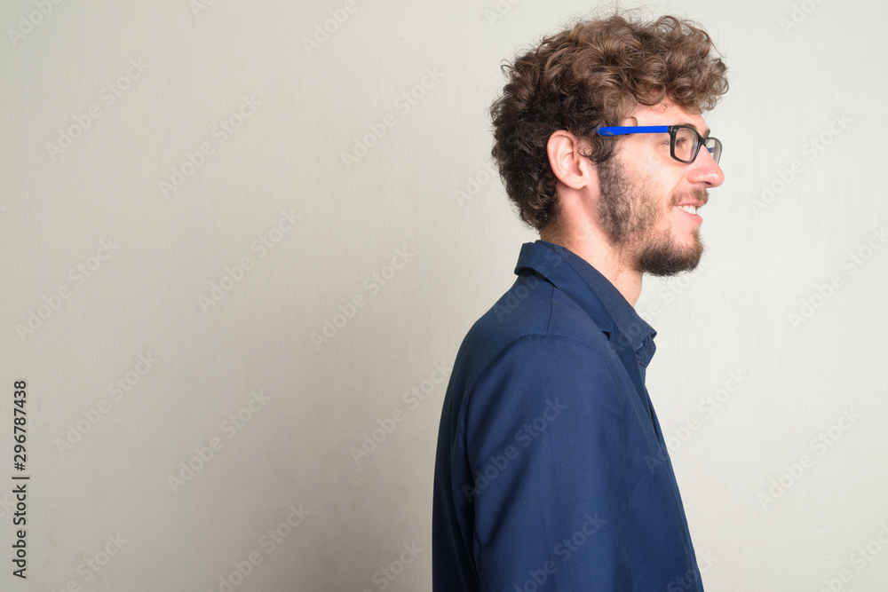 Fototapeta premium Closeup profile view of happy young bearded businessman with eyeglasses smiling