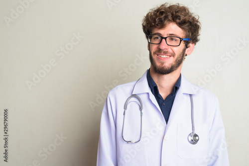 Face of happy young bearded man doctor with eyeglasses thinking