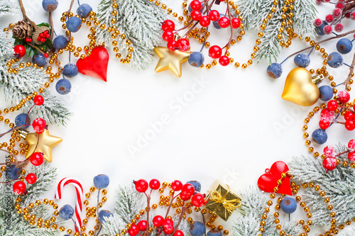 Christmas composition with holly berries, snowflake and green fir branch on white background. Xmas flat lay top view on stucco texture with copy space