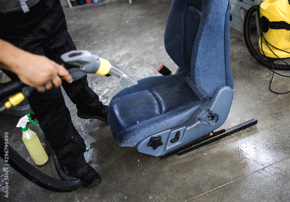 An auto service worker prepares and cleans the car seat