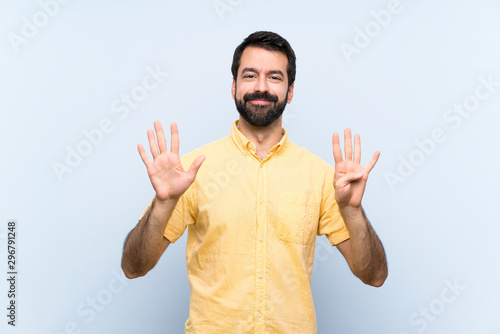 Young man with beard over isolated blue background counting nine with fingers