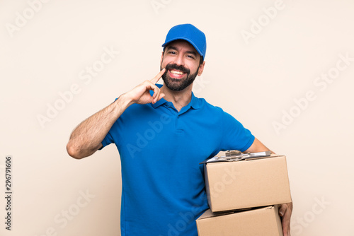 Delivery man with beard over isolated background smiling with a happy and pleasant expression