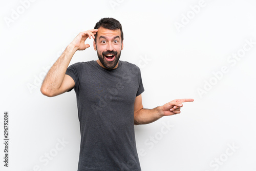 Cuadro en lienzo Young handsome man over isolated white background surprised and pointing finger