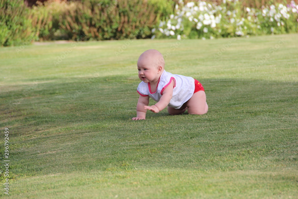 LITTLE GIRL CRAWLING ON THE GREEN GRASS LITTLE GIRL CRAWLING ON THE GREEN GRASS