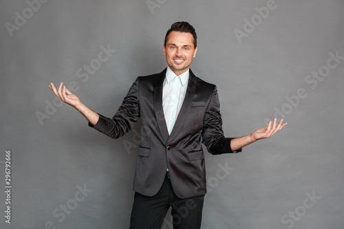 Businessman studio standing isolated on grey hands aside smiling cheerful