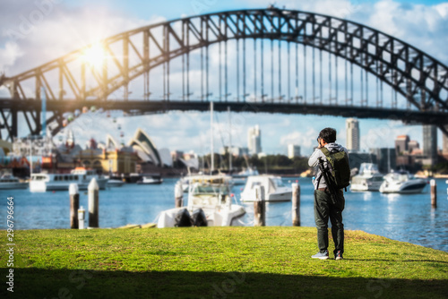 Canvas Print Traveller man young backpacker standing and using a professional Mirrorless DSLR camera take photo beautiful of Sydney city skyline with Sydney harbour bridge north shore in Australia