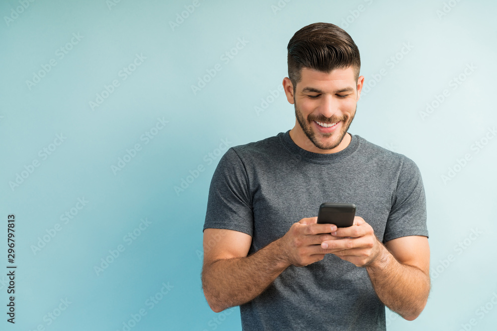 Attractive Hispanic Male Surfing On Mobile Phone - obrazy, fototapety, plakaty 