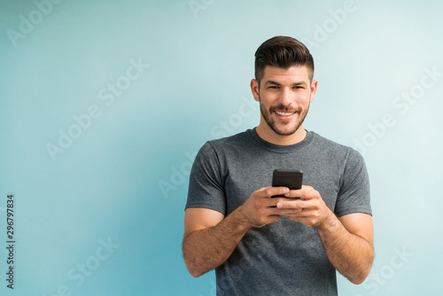 Handsome Man Texting On Smartphone Against Turquoise Background