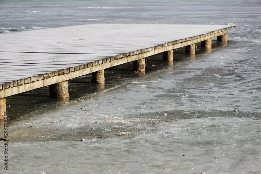 pier on the lake. Wooden bridge in forest in winter time with blue frozen lake. Lake for fishing with pier