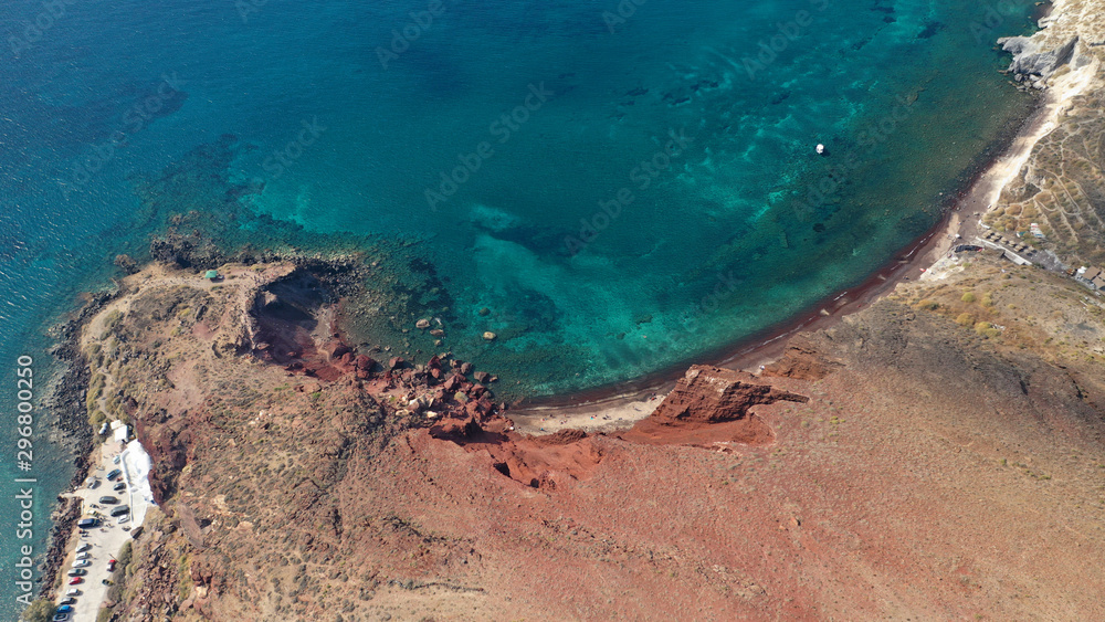 Obraz premium Aerial drone photo of iconic famous red rocky volcanic beach with deep turquoise sea visited by sail boats, Santorini island, Cyclades, Greece