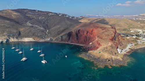 Aerial drone photo of iconic famous red rocky volcanic beach with deep turquoise sea visited by sail boats, Santorini island, Cyclades, Greece