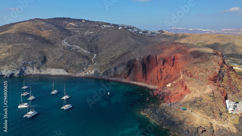 Aerial drone photo of iconic famous red rocky volcanic beach with deep turquoise sea visited by sail boats, Santorini island, Cyclades, Greece © aerial-drone