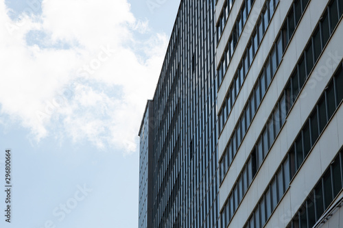 Modern high building business centre or apartment with many windows, sky with clouds on one side. Bottom view, diagonal view.