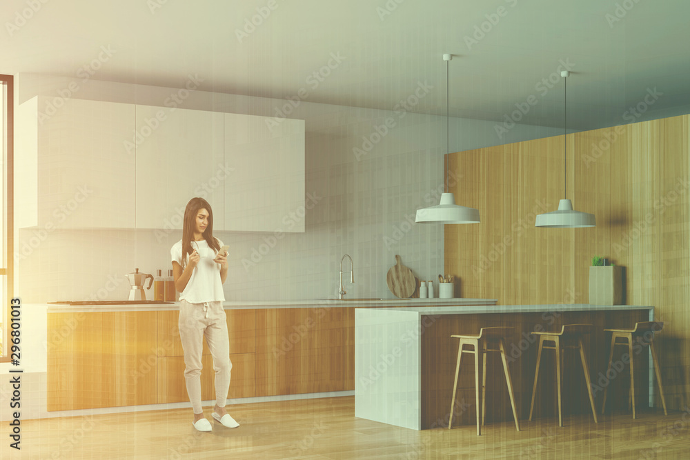 Woman in white and wood kitchen, bar and stools Woman in white and wood kitchen, bar and stools