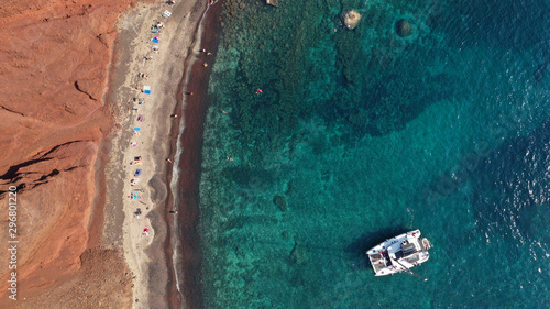 Aerial drone photo of iconic famous red rocky volcanic beach with deep turquoise sea visited by sail boats, Santorini island, Cyclades, Greece © aerial-drone