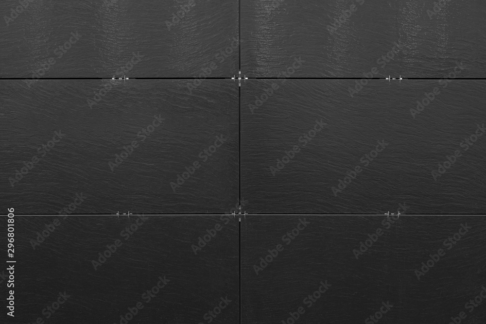 Black uneven surface of building wall with bracketed tiles Black uneven surface of building wall with bracketed tiles