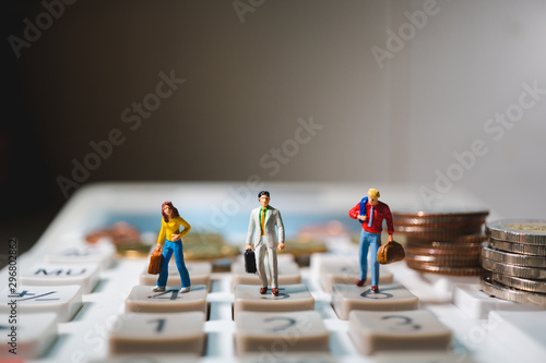 Miniature people, group of business team standing on calculator with stack coins using as business and financial concept