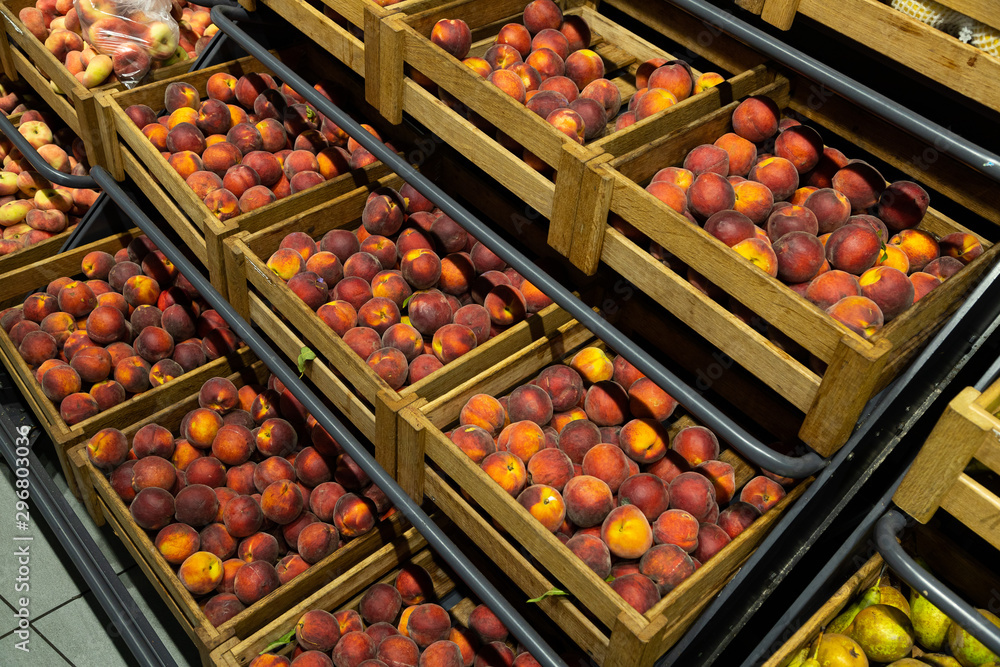 Diagonal view of wooden lug boxes with soft and mellow peaches on counter in supermarket