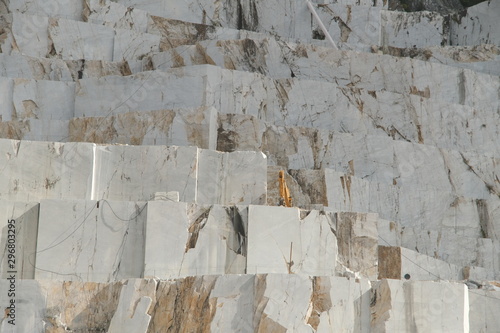 White Carrara marble quarry in Tuscany. Mountains of the Apuan Alps, blue sky and a mechanical excavator..