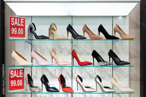 Show-window with shelves with heeled shoes of different colors with red tablet informing about sale