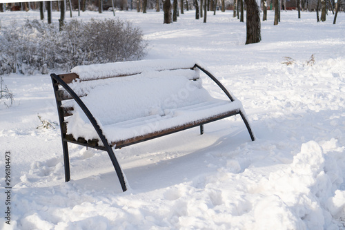 Wallpaper Mural A view of the wooden snow-covered bench with a large layer of snow against the background of snowy bushes in winter park. Torontodigital.ca