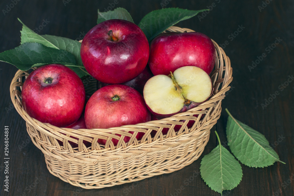 red fresh apples. apples in a wicker basket on a wooden table closeup. background with apples and leaves. crop of apples. red fresh apples. apples in a wicker basket on a wooden table closeup. background with apples and leaves. crop of apples.