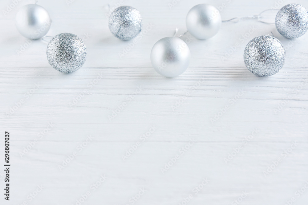 Row of Shiny Christmas balls with selective focus on a white wooden background. Christmas and New Year flat lay. New Year 2020 flat lay with silver decorative ball on white textured background 