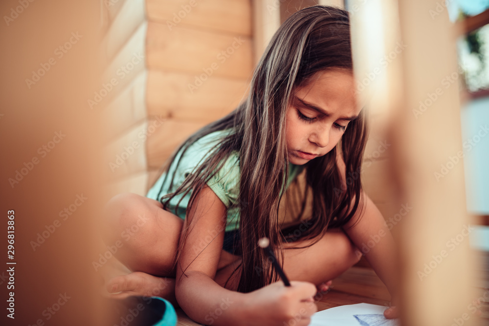 Girl sitting in the treehouse and drawing with colored pencils Girl sitting in the treehouse and drawing with colored pencils